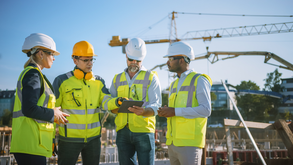 Diverse,Team,Of,Specialists,Use,Tablet,Computer,On,Construction,Site. Diverse,Team,Of,Specialists,Use,Tablet,Computer,On,Construction,Site.